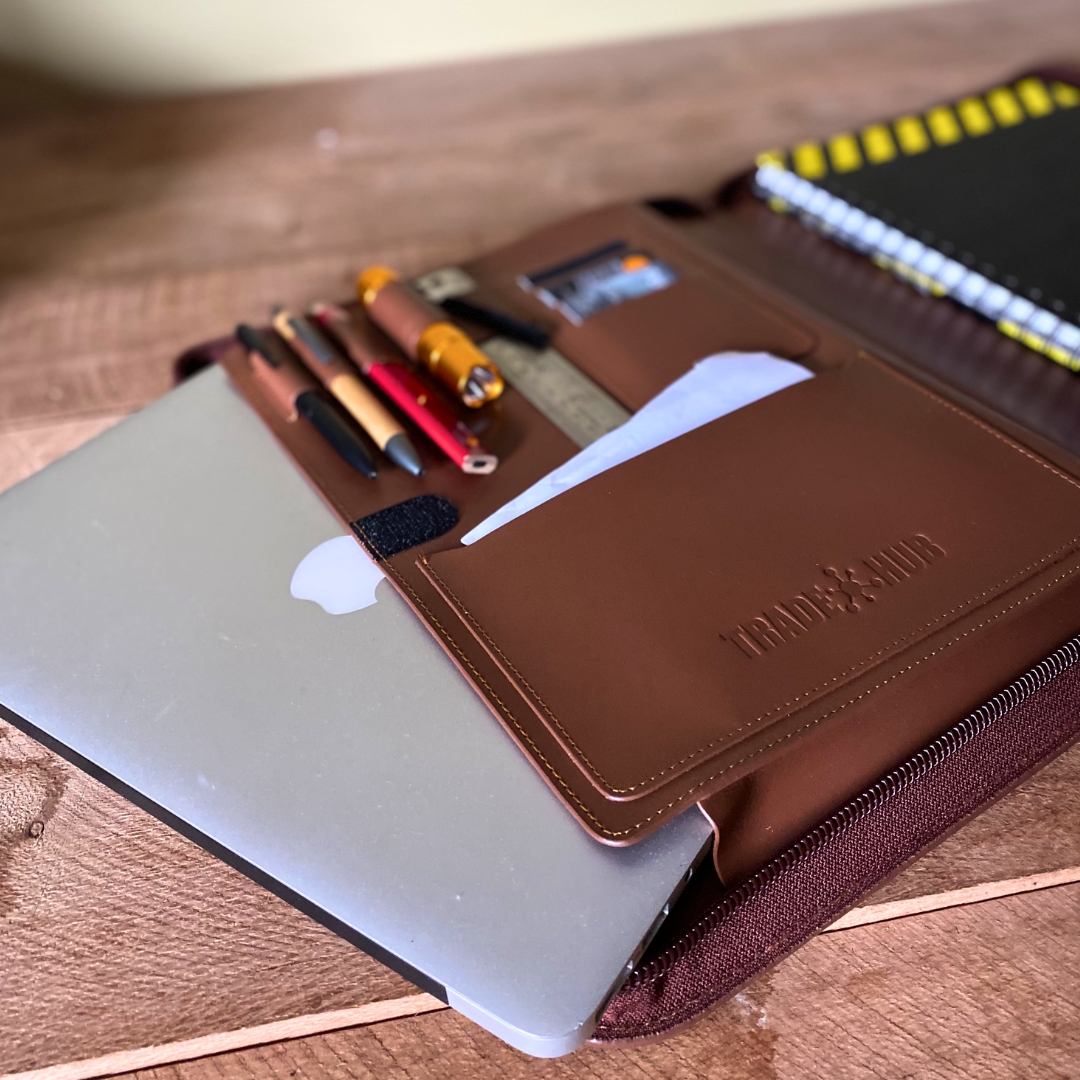 TradeHub folder with pens, torch and ruler beside MacBook and notepad on timber desk